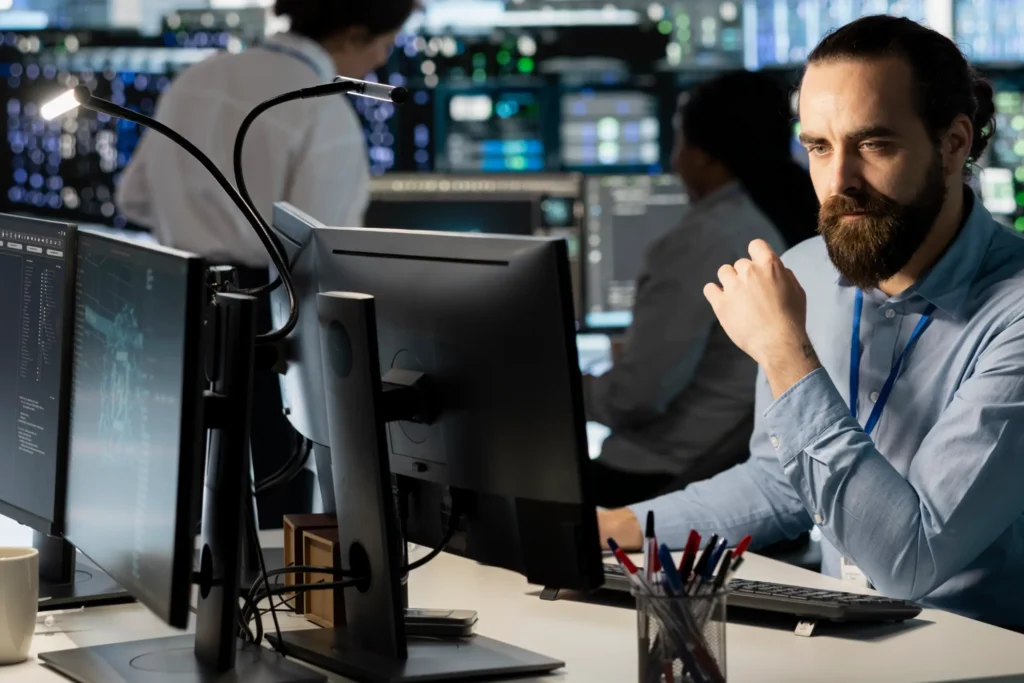Profissional de Site Reliability Engineering analisando telas para manter alta disponibilidade de sistemas