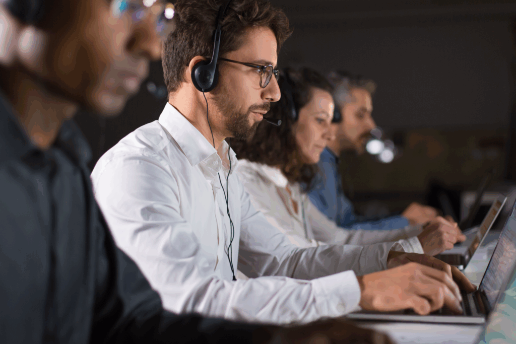 Profissionais de service desk atendendo clientes com headsets e laptops em escritório
